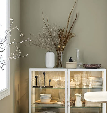 Witte keramische vaas gevuld met decoratieve bloemen