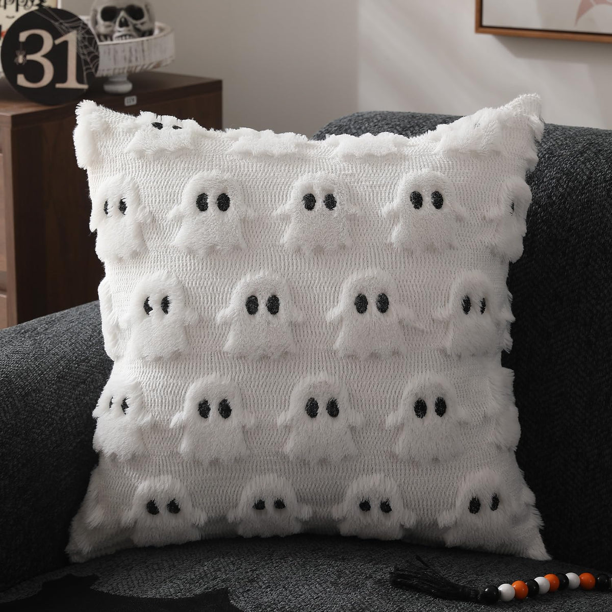 Witte sierkussenhoes met spookmotief op een bank