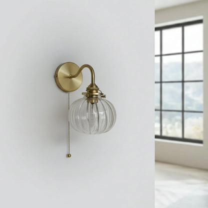Detail van de glazen kap en goudkleurige metalen fitting van de wandlamp