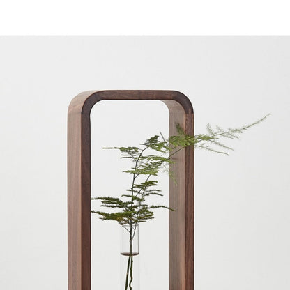 Stekjes in glazen buizen geplaatst in een strak houten frame