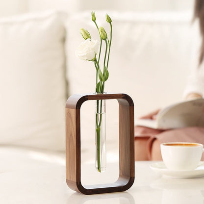 Detail van de stekjesvaas met transparante glasbuizen en houten afwerking